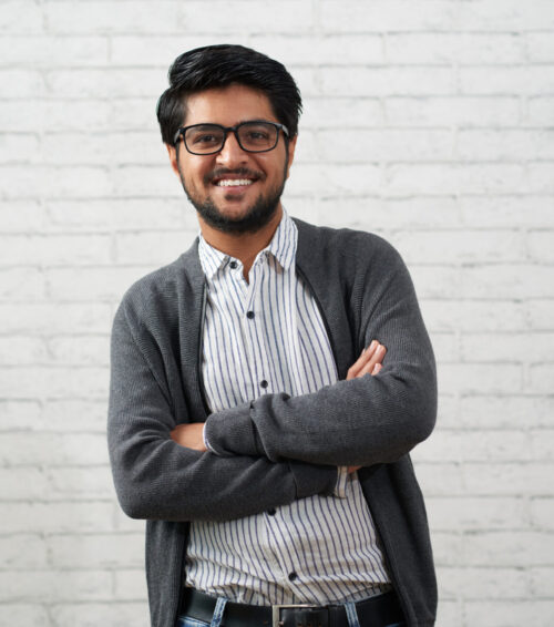 Portrait of confident handsome Indian man smiling and looking at camera